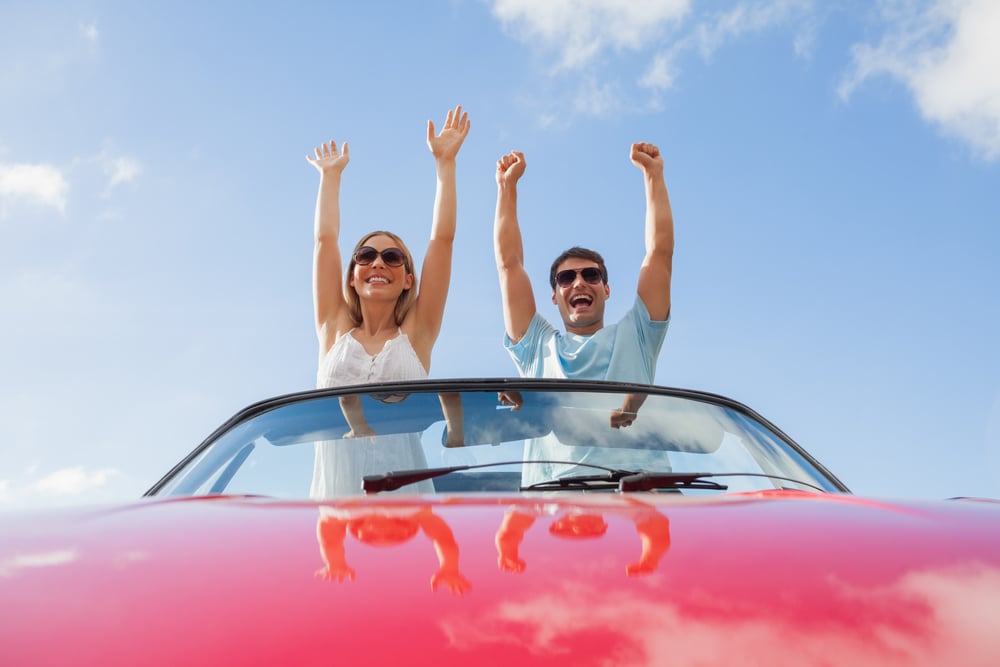 Crazy couple standing in red cabriolet on a sunny day Crazy couple standing in red cabriolet on a sunny day